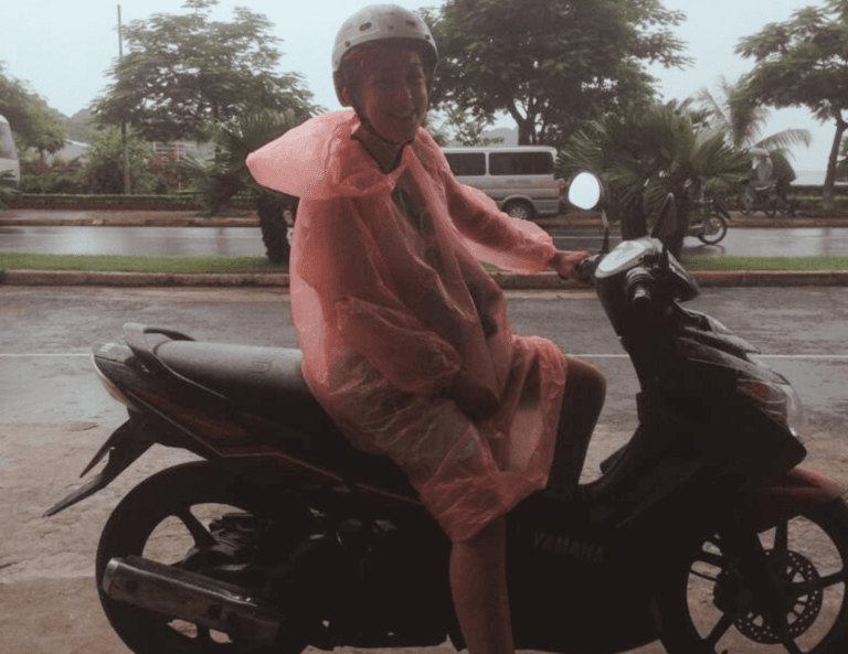 A person on a scooter with a rain coat in the rain