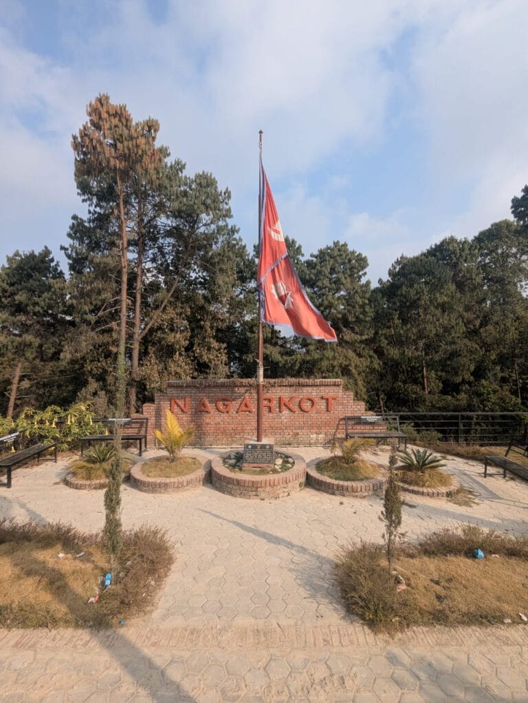 A nepalese flag in front of a sign of Nagarkot